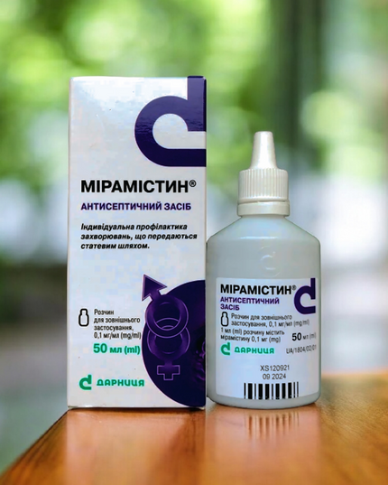 Mipamistin bottle and box on a wooden surface with a blurred green background