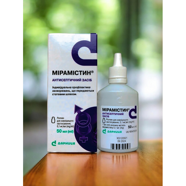 Mipamistin bottle and box on a wooden surface with a blurred green background