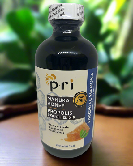 Bottle of Pri Manuka Honey Propolis Cough Elixir on a wooden surface with a blurred green background
