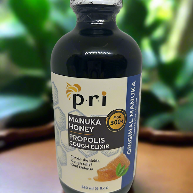 Bottle of Pri Manuka Honey Propolis Cough Elixir on a wooden surface with a blurred green background