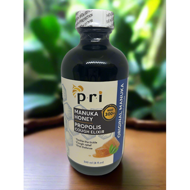 Bottle of Pri Manuka Honey Propolis Cough Elixir on a wooden surface with a blurred green background