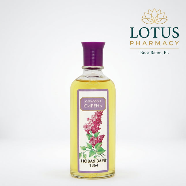 A clear glass bottle filled with pale yellow liquid, topped with a purple cap, and featuring a front label with a purple border, a lilac flower illustration, and Cyrillic text reading 'ОДЕКОНОМ СИРЕНЬ' and 'НОВАЯ ЗАРЯ 1864'.